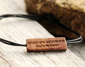 May include: A wooden bracelet with black cord and a wooden tag that reads "37°21'27.0"N 120°25'56.8"W You're My Person".