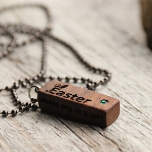 Peut inclure: Un collier avec un pendentif en bois et une pierre pr&eacute;cieuse verte. Le pendentif est grav&eacute; des mots "Let it be the Water" et "Easter".