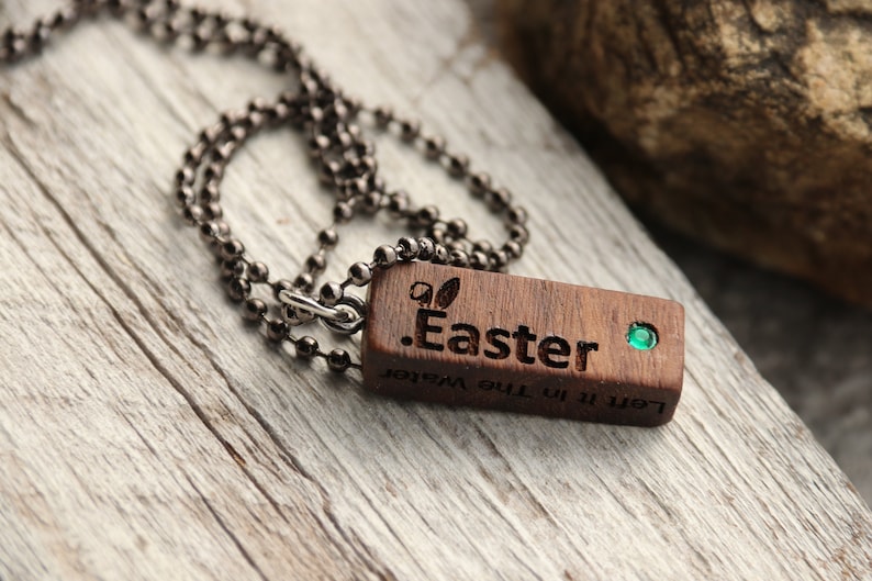 Peut inclure: Un collier avec un pendentif en bois et une pierre pr&eacute;cieuse verte. Le pendentif est grav&eacute; avec le texte ".Easter" et "Left it in the water".