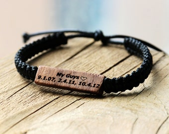 May include: Black braided bracelet with a wooden tag that reads "My Guys 9.1.07, 2.4.11, 10.4.12" with a heart symbol.