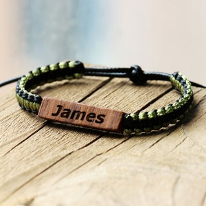 May include: A black and green braided bracelet with a wooden tag that says "James".