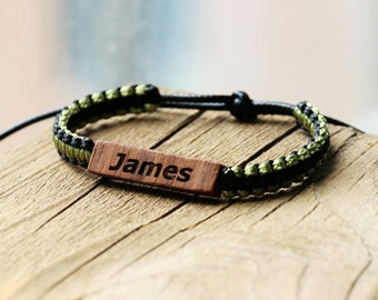 May include: A black and green braided bracelet with a wooden tag that says "James".