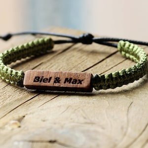 May include: A green braided bracelet with a wooden bead engraved with the text "Biel & Max".