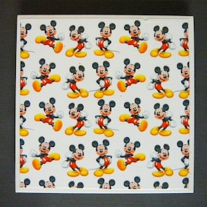 May include: White background with a repeating pattern of Mickey Mouse. Mickey Mouse is wearing red shorts and yellow shoes. He is smiling and waving.