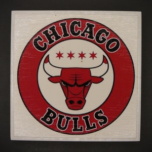 May include: A red, white, and black circular logo with the text "CHICAGO BULLS" in a black, bold font. A red bull with black horns and a black nose is in the center of the logo. Three white stars are above the bull's head.