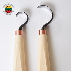 Może przedstawiać: Dwa narzędzia do rzeźbienia w drewnie z miedzianymi akcentami i czarnymi metalowymi ostrzami. Narzędzia mają drewniane uchwyty z okrągłym logo na dole. Logo to stylizowana litera "E" w kółku.