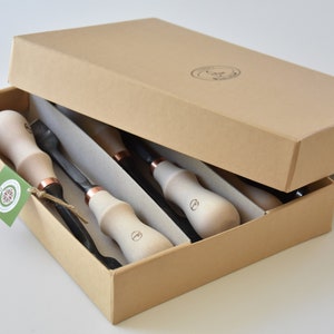 May include: A set of four wood carving tools with wooden handles and copper accents, packaged in a brown cardboard box.