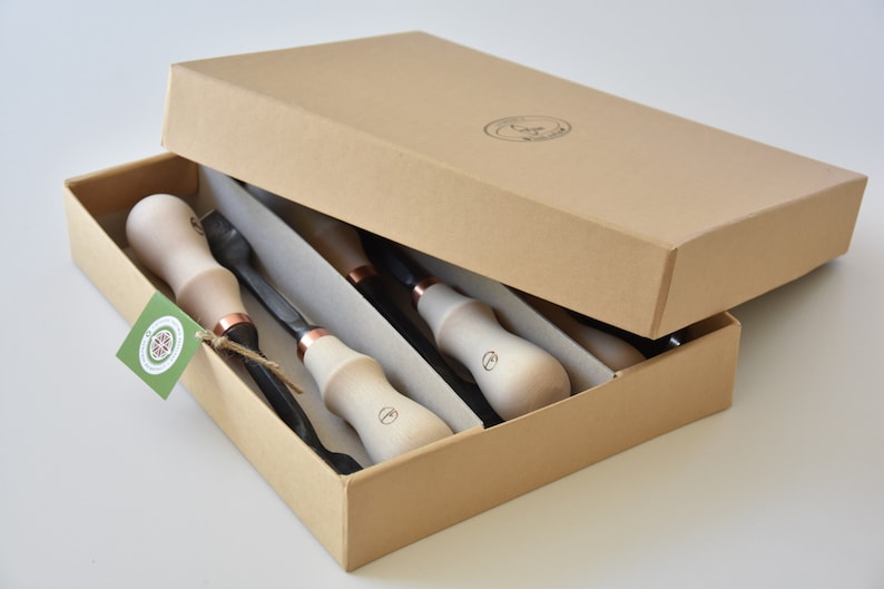 May include: A set of four wood carving tools with wooden handles and copper accents, packaged in a brown cardboard box.