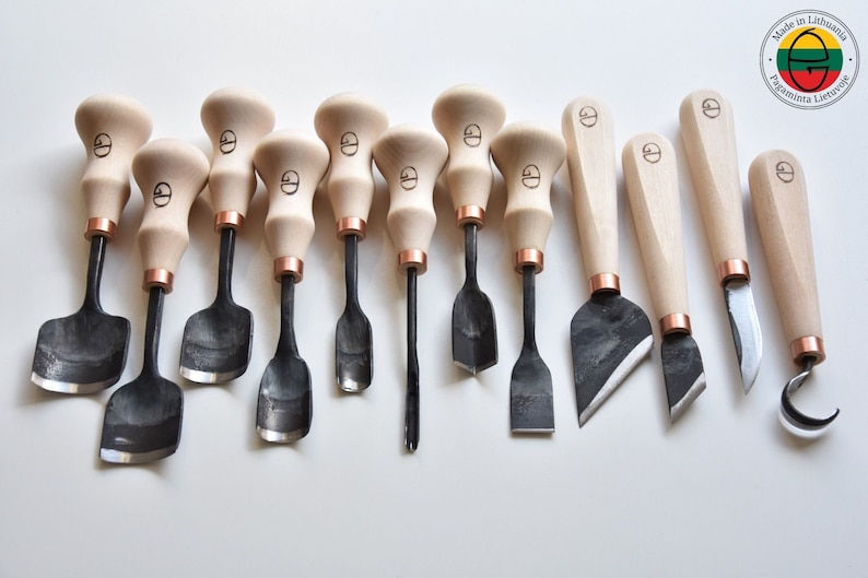 May include: A set of 12 wood carving tools with wooden handles and black metal blades. The tools have different shapes and sizes, including a hook, a knife, and a variety of gouges. The tools are made in Lithuania.