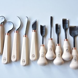 May include: Set of 12 wood carving tools with wooden handles and copper accents. The tools have different shapes and sizes for various carving techniques. Made in Lithuania.