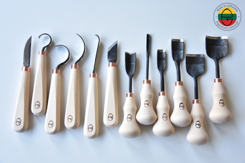 May include: Set of 12 wood carving tools with wooden handles and copper accents. The tools have different shapes and sizes for various carving techniques. Made in Lithuania.