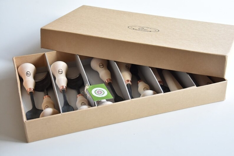 May include: A set of 10 wood carving tools with copper accents, organised in a cardboard box with a label that reads "Leather Carving Tools".