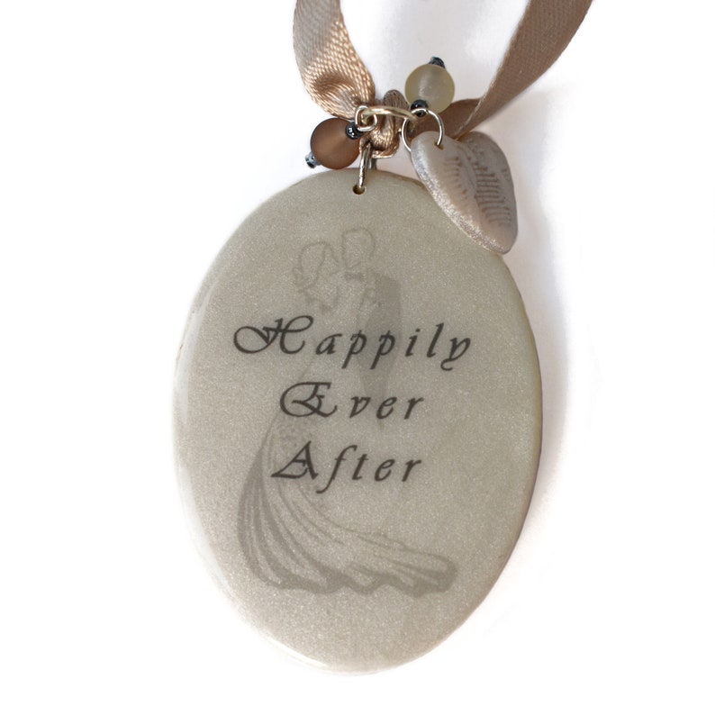 Closeup of tag front with image of bride and groom, text reading Happily Ever After, and with Czech glass beads and polymer clay heart charm hanging from taupe satin ribbon.