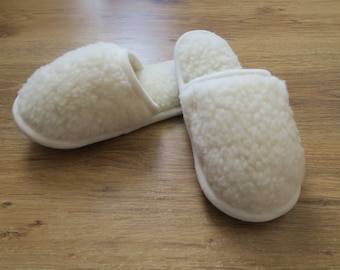 May include: A pair of white sheepskin slippers. The slippers are soft and fluffy, and they have a simple design.