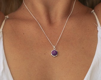 May include: A silver chain necklace with a purple gemstone pendant.