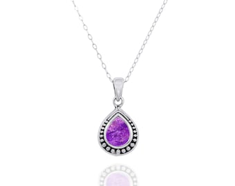 May include: A silver chain necklace with a purple teardrop pendant. The pendant has a beaded border and a textured purple stone.