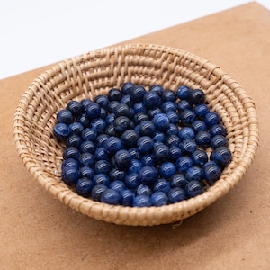 May include: A woven basket filled with smooth, round, blue gemstone beads.