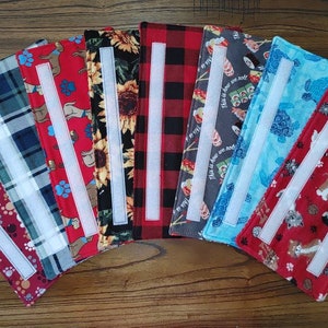 May include: A set of ten fabric strips with different patterns, including paw prints, plaid, sunflowers, and cats. Each strip has a white velcro strip sewn on for attaching to a surface.