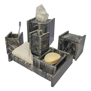 Puede incluir: Un juego de baño de mármol gris con un jabonera, un portacepillos de dientes, una caja de pañuelos, un dispensador de jabón y una bandeja.