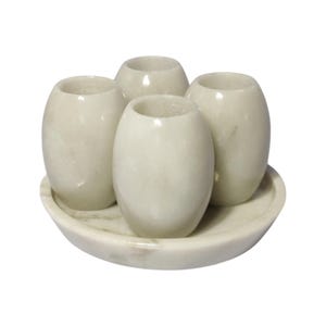 Puede incluir: Juego de cuatro vasos de chupito de mármol blanco en una bandeja de mármol blanco.