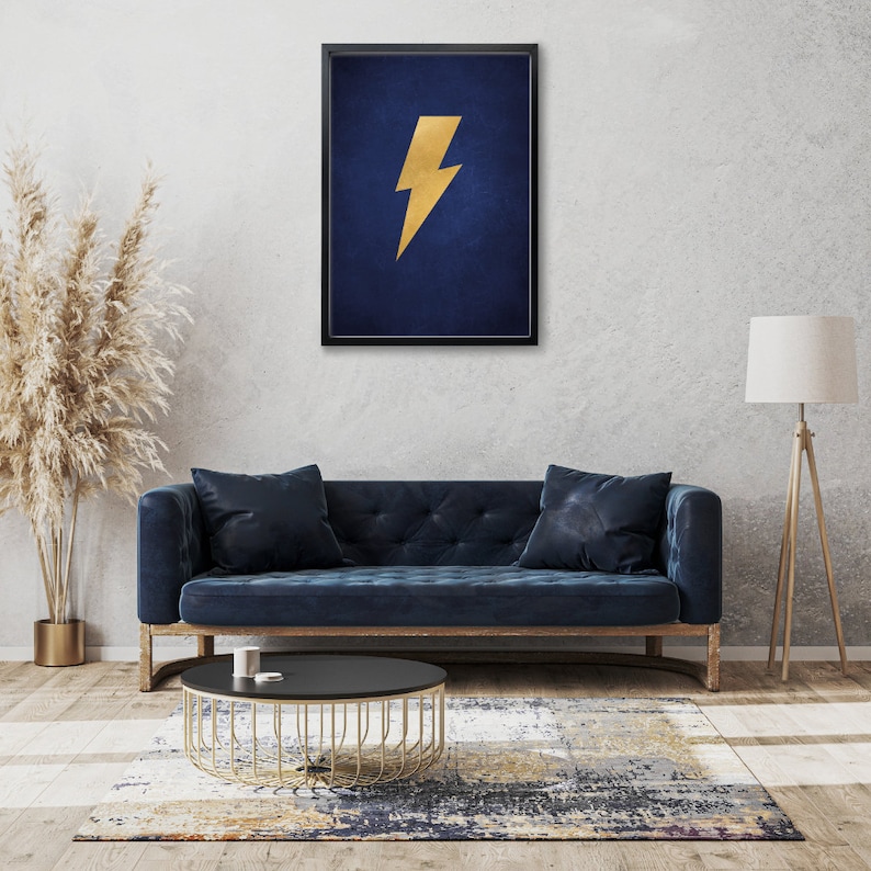 May include: A framed print with a gold lightning bolt on a dark blue background. The print is hanging on a wall above a blue sofa.