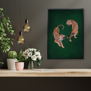Op de afbeelding: Een ingelijste print van twee tijgers op een groene achtergrond. De tijgers kijken elkaar aan, een ligt en de ander staat.