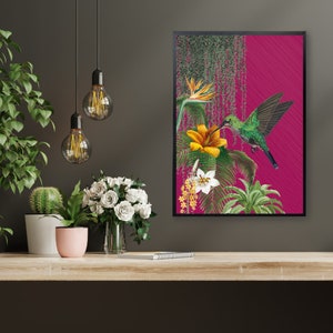 K&ouml;nnte beinhalten: Ein gerahmter Druck mit einem Kolibri mit gr&uuml;nen und schwarzen Federn, der Nektar aus einer gelben Blume trinkt. Der Hintergrund ist leuchtend pink mit gr&uuml;nem Laub.