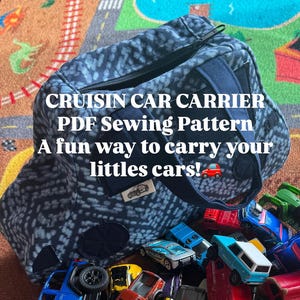May include: A blue patterned fabric bag with a zipper closure and a small label, containing a collection of various colorful die-cast toy cars and trucks. The text on the bag reads: CRUISIN CAR CARRIER PDF Sewing Pattern A fun way to carry your littles cars!