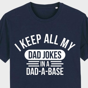 Könnte beinhalten: Ein marineblaues T-Shirt mit weißem Text, der "I keep all my dad jokes in a dad-a-base" lautet.