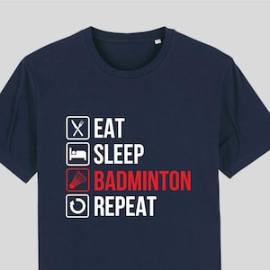 May include: A navy blue t-shirt with a white graphic that says "Eat, Sleep, Badminton, Repeat" with a badminton shuttlecock icon next to the word "Badminton".