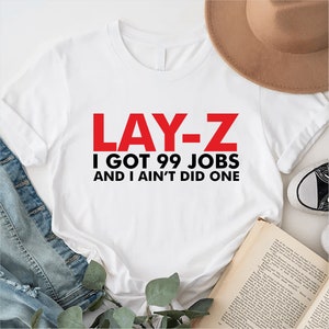May include: White t-shirt with the text "LAY-Z I GOT 99 JOBS AND I AIN'T DID ONE" in red and black lettering.