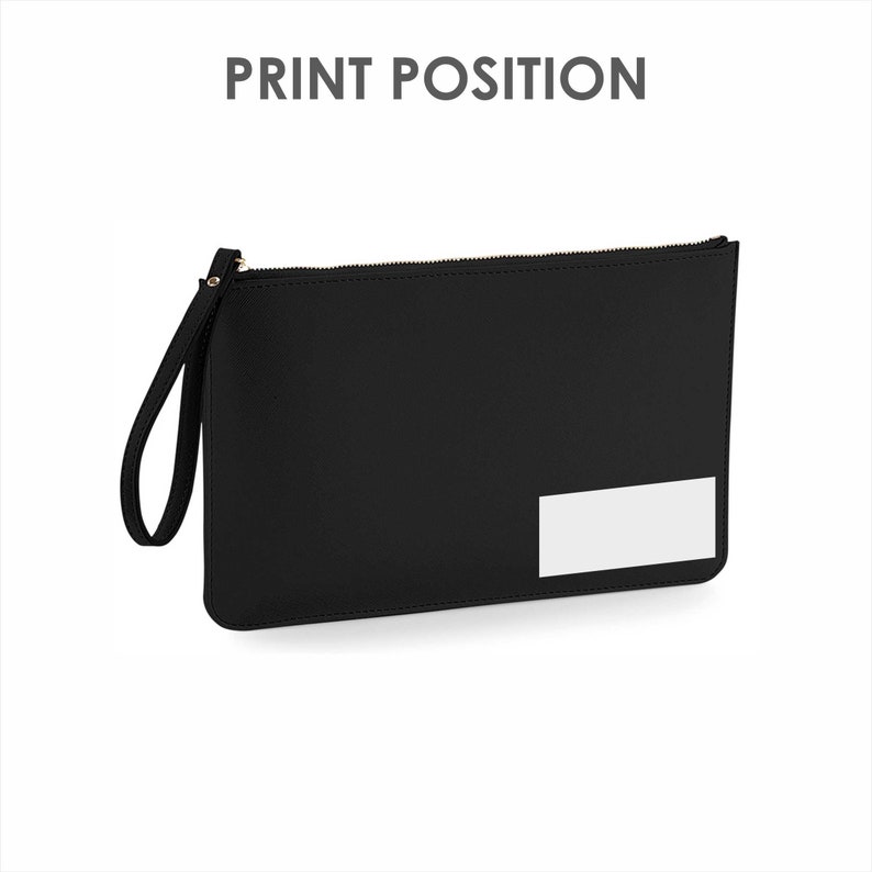 Op de afbeelding: Zwarte leren clutch met een ritssluiting en een rechthoekige witte patch aan de voorkant. De clutch heeft een polsbandje.