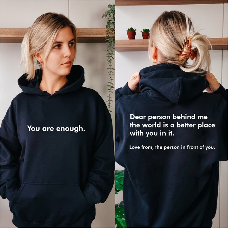May include: Black hooded sweatshirt with the text "You are enough." on the front and "Dear person behind me the world is a better place with you in it. Love from, the person in front of you." on the back.