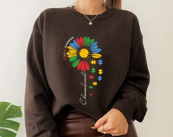May include: A dark brown sweatshirt featuring a colorful sunflower design with puzzle pieces and the words "Autism awareness" and "Choosekind". The sunflower has yellow, red, green, and blue petals.
