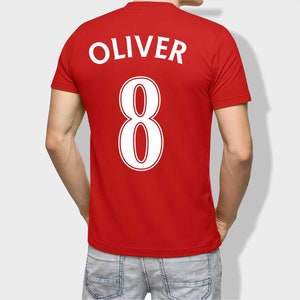 May include: Red t-shirt with the name "Oliver" and the number "8" printed on the back in white.