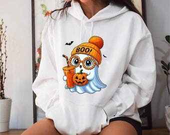 May include: White hoodie featuring a cartoon ghost wearing an orange beanie with the word "BOO!" and glasses. The ghost holds a pumpkin and a drink with a straw. Two black bats are flying above the ghost. The hoodie has a front pocket.