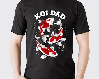 May include: Black t-shirt with a graphic of three red and white koi fish swimming in a circle. The text "KOI DAD" is arched above the fish. The shirt is made of a soft material.