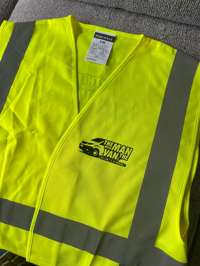 K&ouml;nnte beinhalten: Eine leuchtend gelbe Sicherheitsweste mit reflektierenden silbernen Streifen. Die Weste hat ein schwarzes Logo mit der Aufschrift "The Man With The Van" und den Text "Reliable & Affordable".