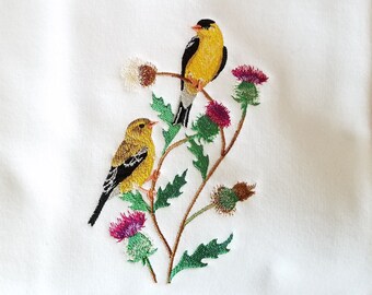 May include: White t-shirt with embroidered yellow birds perched on a branch with green leaves and purple thistle flowers.