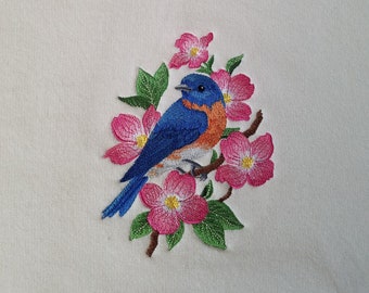 May include: A white sweatshirt with an embroidered design of a bluebird perched on a branch with pink flowers.