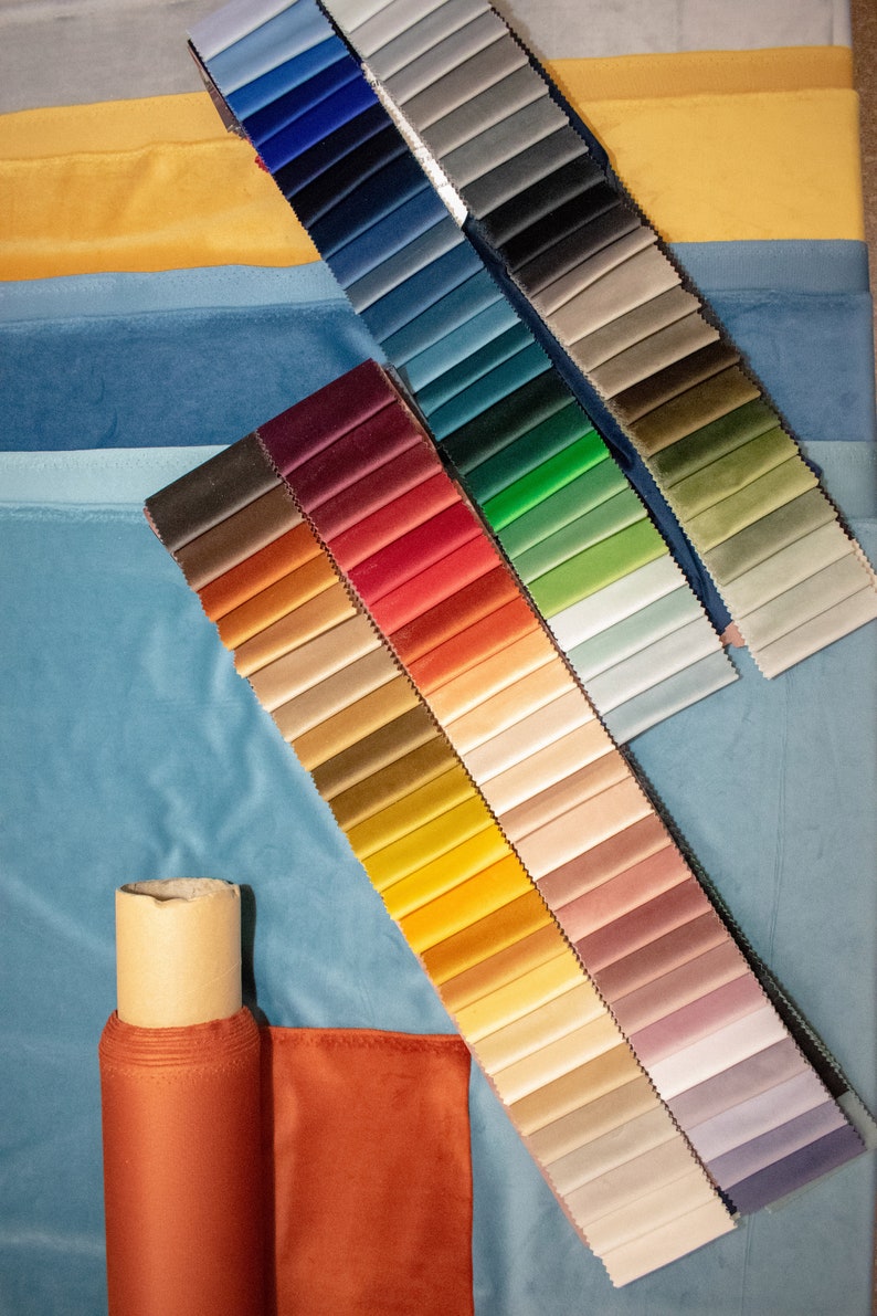 May include: A fabric swatch book with a variety of colors, including blue, green, red, yellow, and brown. The swatches are arranged in rows and columns, and there is a roll of fabric in the lower left corner of the image.