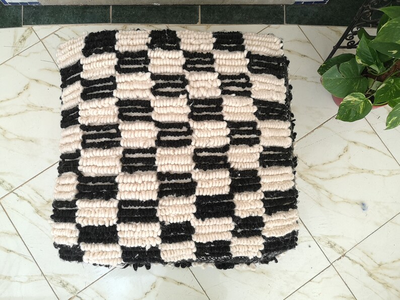 May include: Black and white checkered floor cushion made of fluffy yarn.