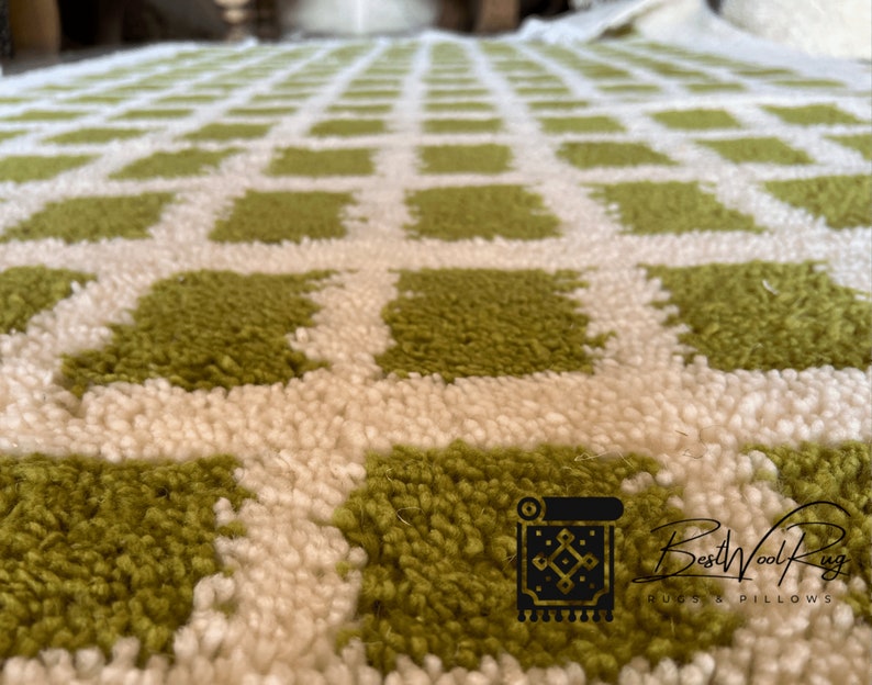 May include: Close-up of a green and white checkered rug with a fluffy texture. The rug is made of wool and has a modern design.