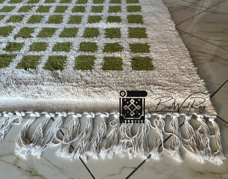 May include: A white and green wool rug with a geometric pattern. The rug has a fringe border and the text "BestWoolRug" is visible in the bottom right corner.
