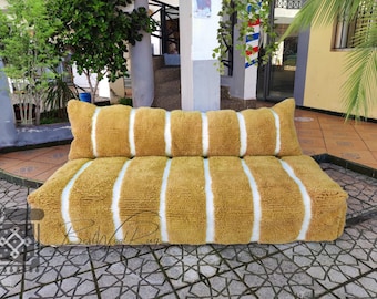 Può includere: Un cuscino per divano a strisce, soffice, giallo e bianco con un design trapuntato. Il cuscino è seduto su un pavimento piastrellato.