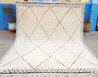May include: A white Moroccan rug with a black diamond pattern. The rug has a fringe border and is folded in half.