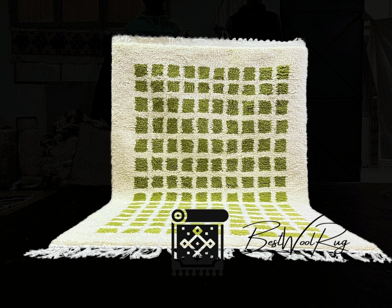 May include: A white wool rug with a geometric pattern of green squares. The rug has a fringe border and the text "BestWoolRug" is visible in the bottom right corner.