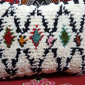May include: White pillow with black and colorful geometric designs. The pillow is made of a fluffy, textured fabric.
