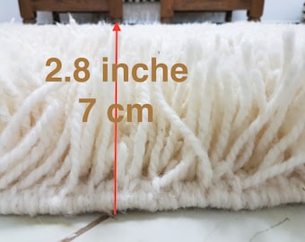 Op de afbeelding: Close-up van een wit shagtapijt met een poolhoogte van 7 cm (2,8 inch).