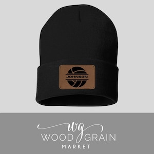 May include: Black knit beanie with a brown leather patch featuring a volleyball graphic and the name "JOHNSON" in white text.